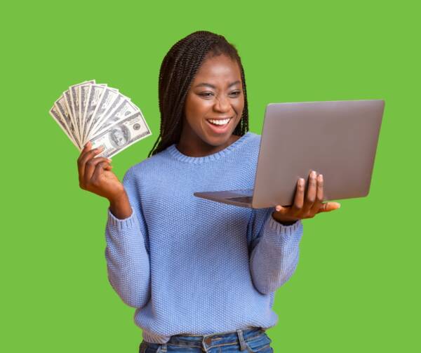 Women looking happily at the screen of the laptop she is holding, while fanning out money